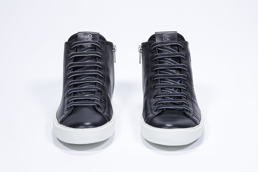 Front view of mid top black sneaker with full leather upper with perforated crown logo, internal zip and white sole.