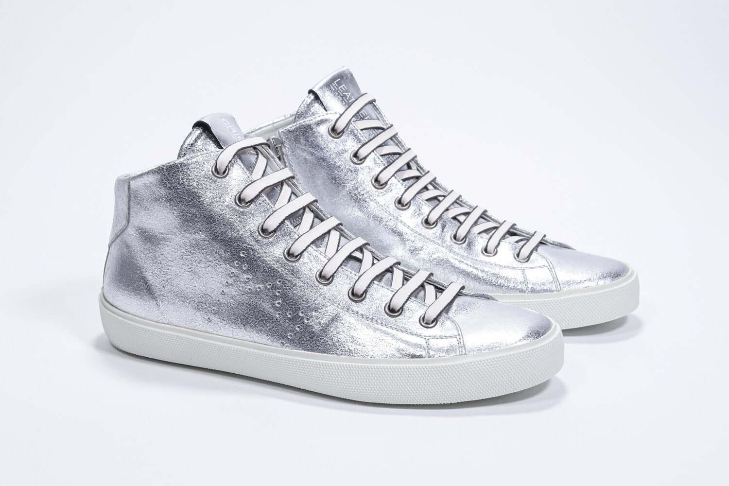 Three quarter front view of mid top silver sneaker with full leather upper with perforated crown logo, internal zip and white sole.