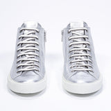 Front view of mid top silver sneaker with full leather upper with perforated crown logo, internal zip and white sole.