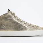 Side profile of mid top gold sneaker with full leather upper with perforated crown logo, internal zip and white sole.