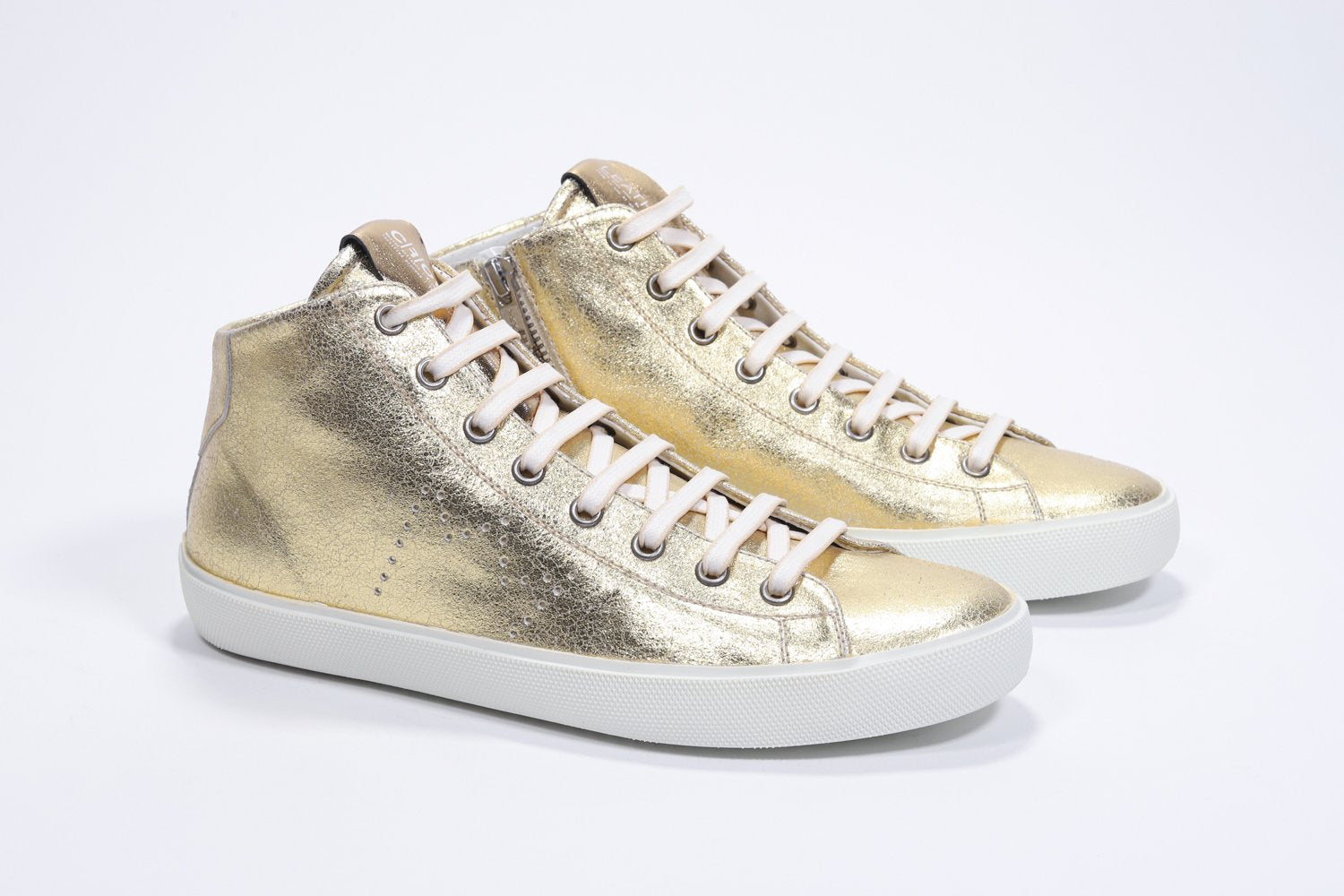 Three quarter front view of mid top gold sneaker with full leather upper with perforated crown logo, internal zip and white sole.