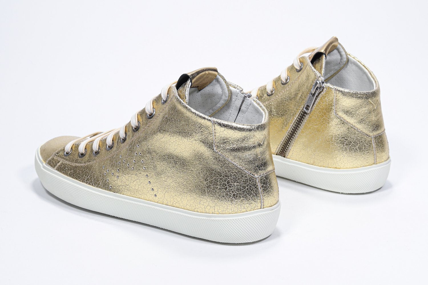 Three quarter back view of mid top gold sneaker with full leather upper with perforated crown logo, internal zip and white sole.