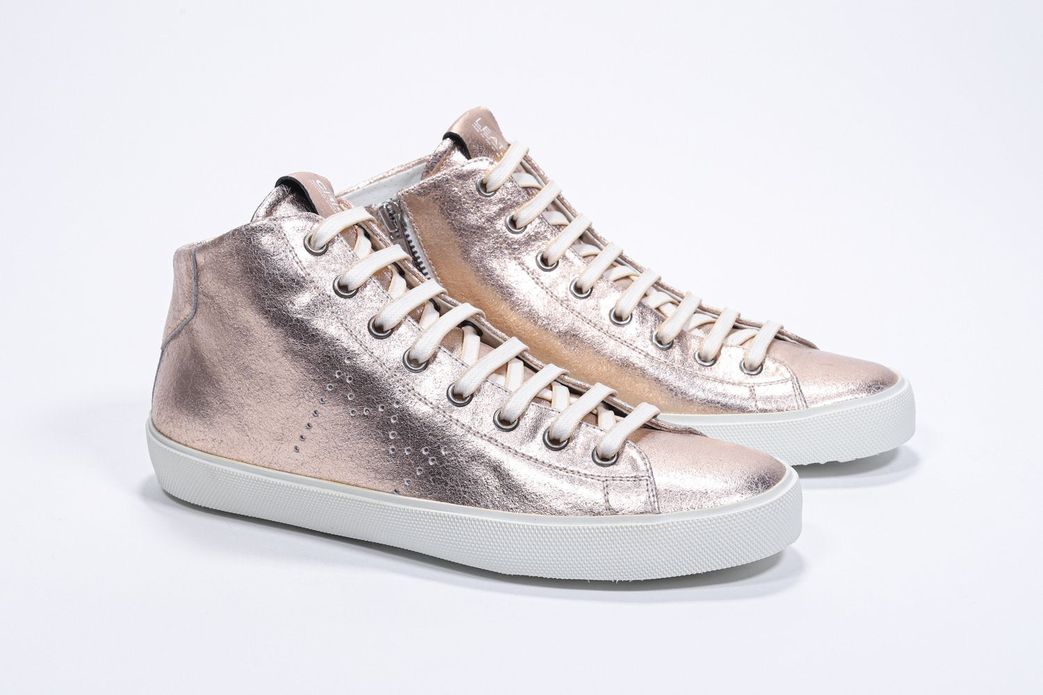 Three quarter front view of mid top rose-gold sneaker with full leather upper with perforated crown logo, internal zip and white sole.