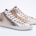 Three quarter front view of mid top rose-gold sneaker with full leather upper with perforated crown logo, internal zip and white sole.