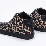 Tre quarti posteriore del modello mid top leopardato sneaker con tomaia in pelle di vitello a pelo pieno, zip interna e suola nera.