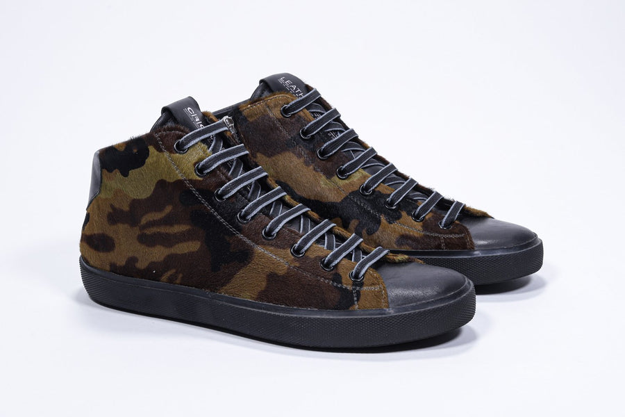 Three quarter front view of mid top camouflage print sneaker with full hair calf leather upper, internal zip and black sole.