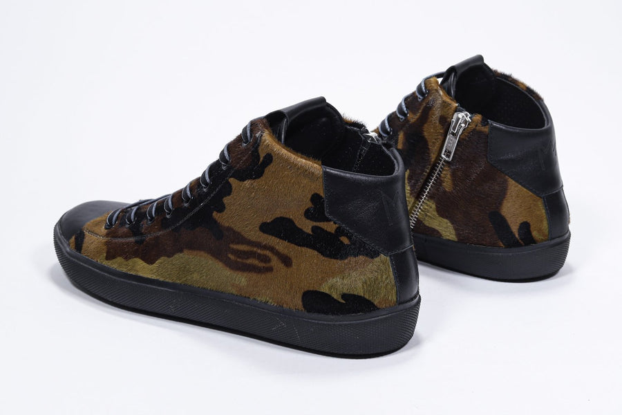 Three quarter back view of mid top camouflage print sneaker with full hair calf leather upper, internal zip and black sole.