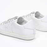 Vista posteriore a tre quarti di BASSE  sneaker  bianco con logo della corona traforato sulla tomaia. Tomaia in pelle e suola in gomma bianca.