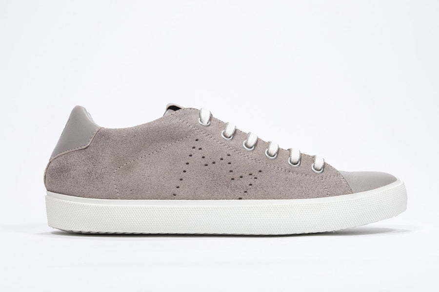 Side profile of low top beige sneaker with perforated crown logo on upper. Full suede upper and white rubber sole.
