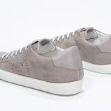 Three quarter back view of low top beige sneaker with perforated crown logo on upper. Full suede upper and white rubber sole.