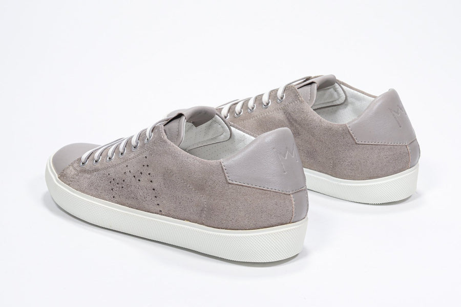 Three quarter back view of low top beige sneaker with perforated crown logo on upper. Full suede upper and white rubber sole.