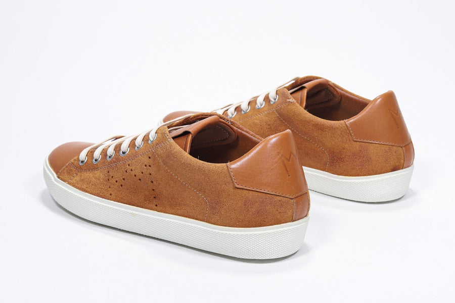 Three quarter back view of low top rust color sneaker with perforated crown logo on upper. Full suede upper and white rubber sole.