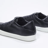 Three quarter back view of low top black sneaker with perforated crown logo on upper. Full leather upper and white rubber sole.