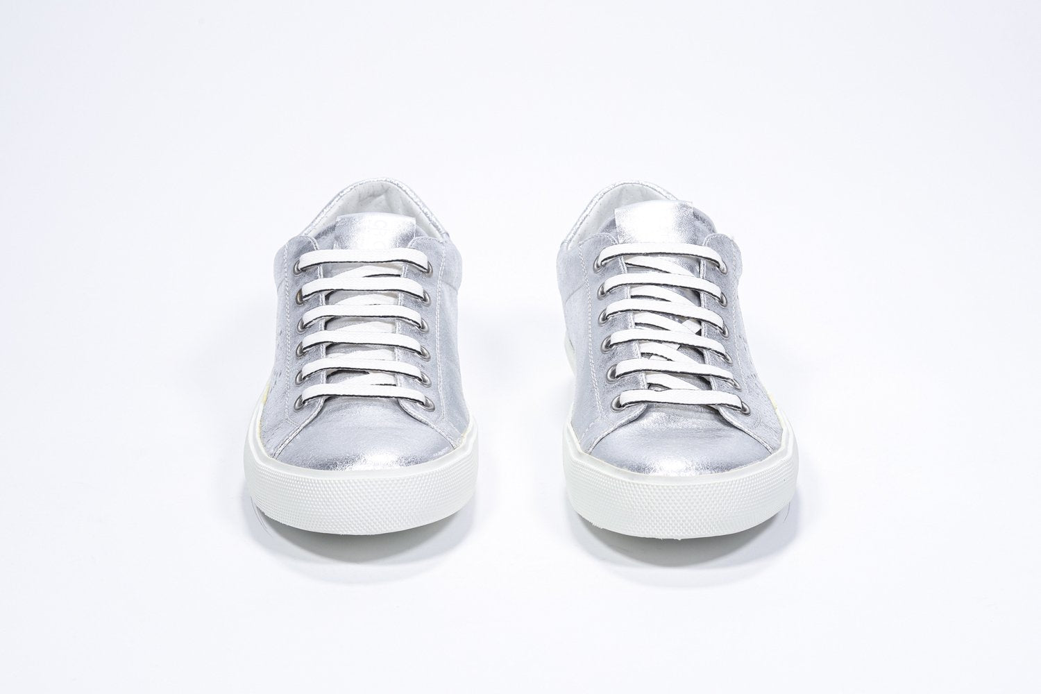 Vue avant de la chaussure basse argentée sneaker avec le logo perforé de la couronne sur la tige. Dessus en cuir métallisé et semelle en caoutchouc blanc.