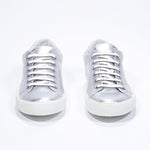 Front view of low top silver sneaker with perforated crown logo on upper. Full metallic leather upper and white rubber sole.