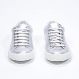 Front view of low top silver sneaker with perforated crown logo on upper. Full metallic leather upper and white rubber sole.