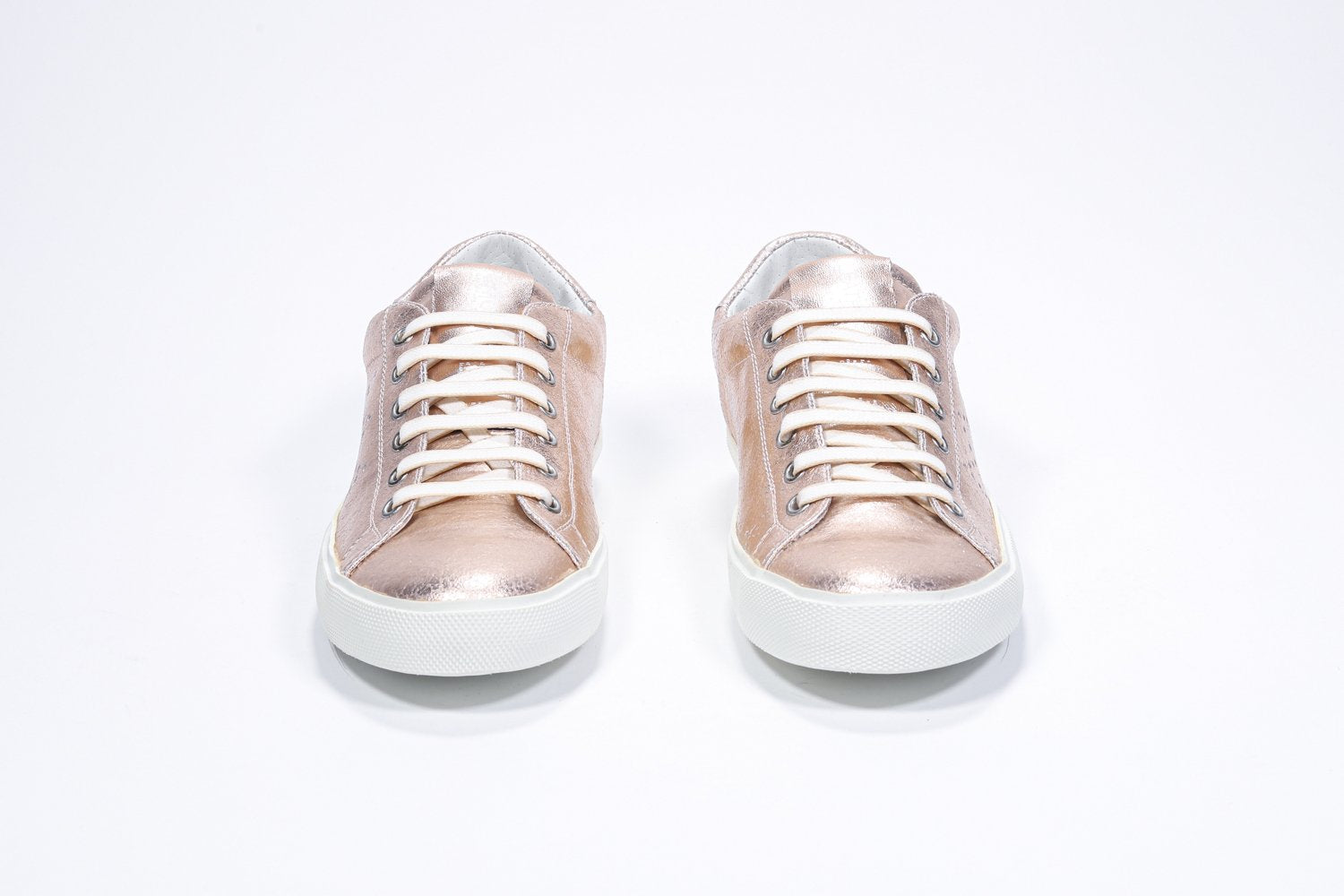 Front view of low top rose-gold sneaker with perforated crown logo on upper. Full metallic leather upper and white rubber sole.