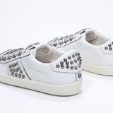 Three quarter back view of low top white sneaker. Full leather upper with studs and vintage rubber sole.