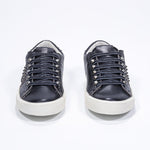 Front view of low top black sneaker. Full leather upper with studs and antique rubber sole.