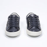 Front view of low top black sneaker. Full leather upper with studs and antique rubber sole.