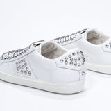 Three quarter back view of low top white sneaker. Full leather upper with studs and white rubber sole.