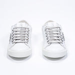 Front view of low top white sneaker. Full leather upper with studs and white rubber sole.