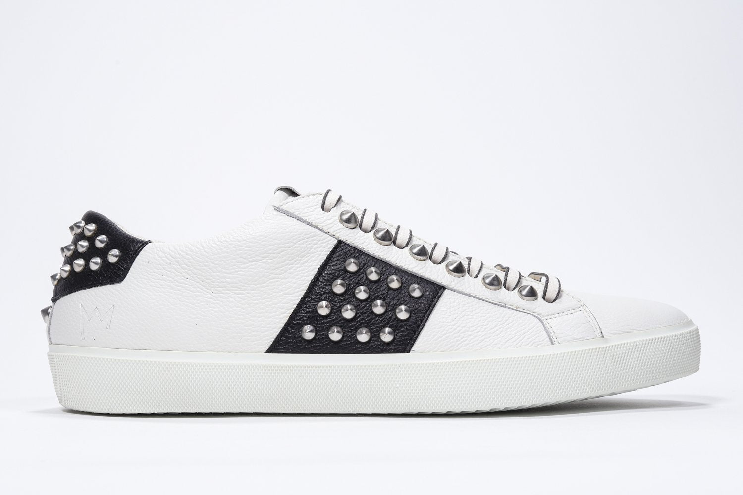Profil latéral d'un bas blanc et noir sneaker. Tige en cuir avec clous et semelle en caoutchouc blanc.