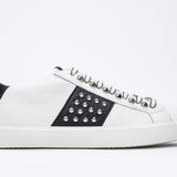 Profilo laterale di BASSE bianco e nero sneaker. Tomaia in pelle con borchie e suola in gomma bianca.