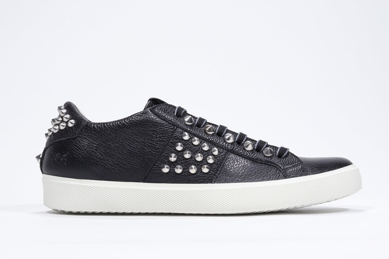 Profilo laterale di BASSE nero sneaker. Tomaia in pelle con borchie e suola in gomma bianca.