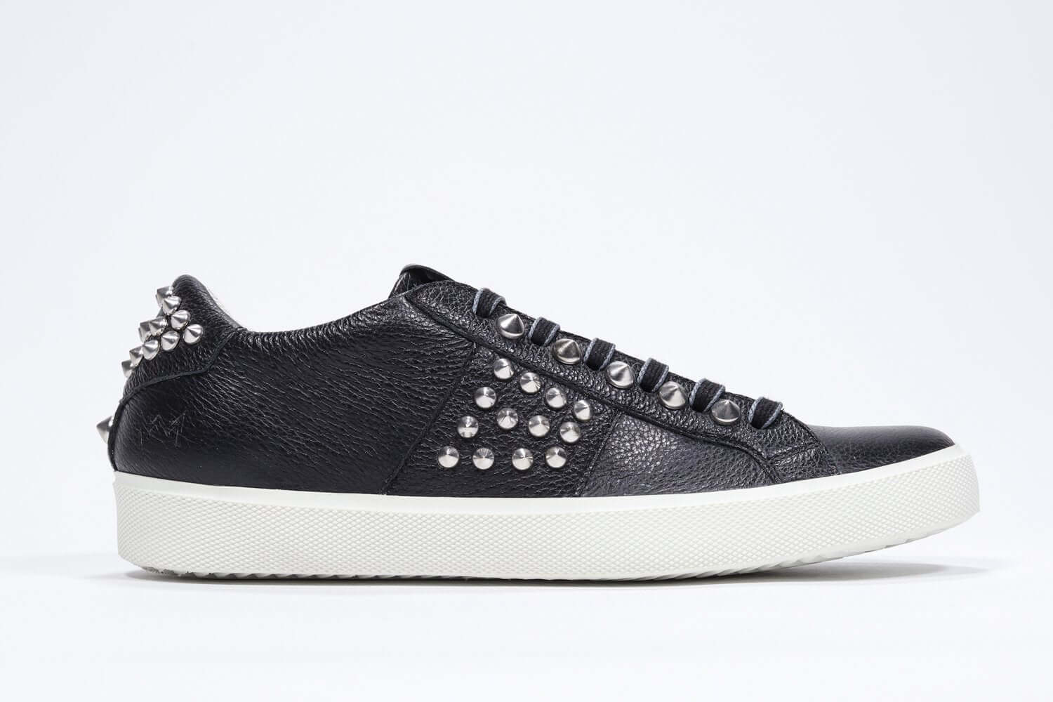 Side profile of low top black sneaker. Full leather upper with studs and white rubber sole.