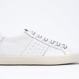 Profilo laterale di BASSE bianco sneaker. Tomaia in pelle con borchie e suola in gomma vintage.