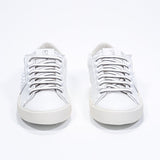 Front view of low top white sneaker. Full leather upper with studs and vintage rubber sole.