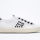 Side profile of low top white sneaker. Full leather upper with studs and vintage rubber sole.