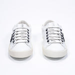 Front view of low top white sneaker. Full leather upper with studs and vintage rubber sole.