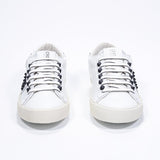 Front view of low top white sneaker. Full leather upper with studs and vintage rubber sole.