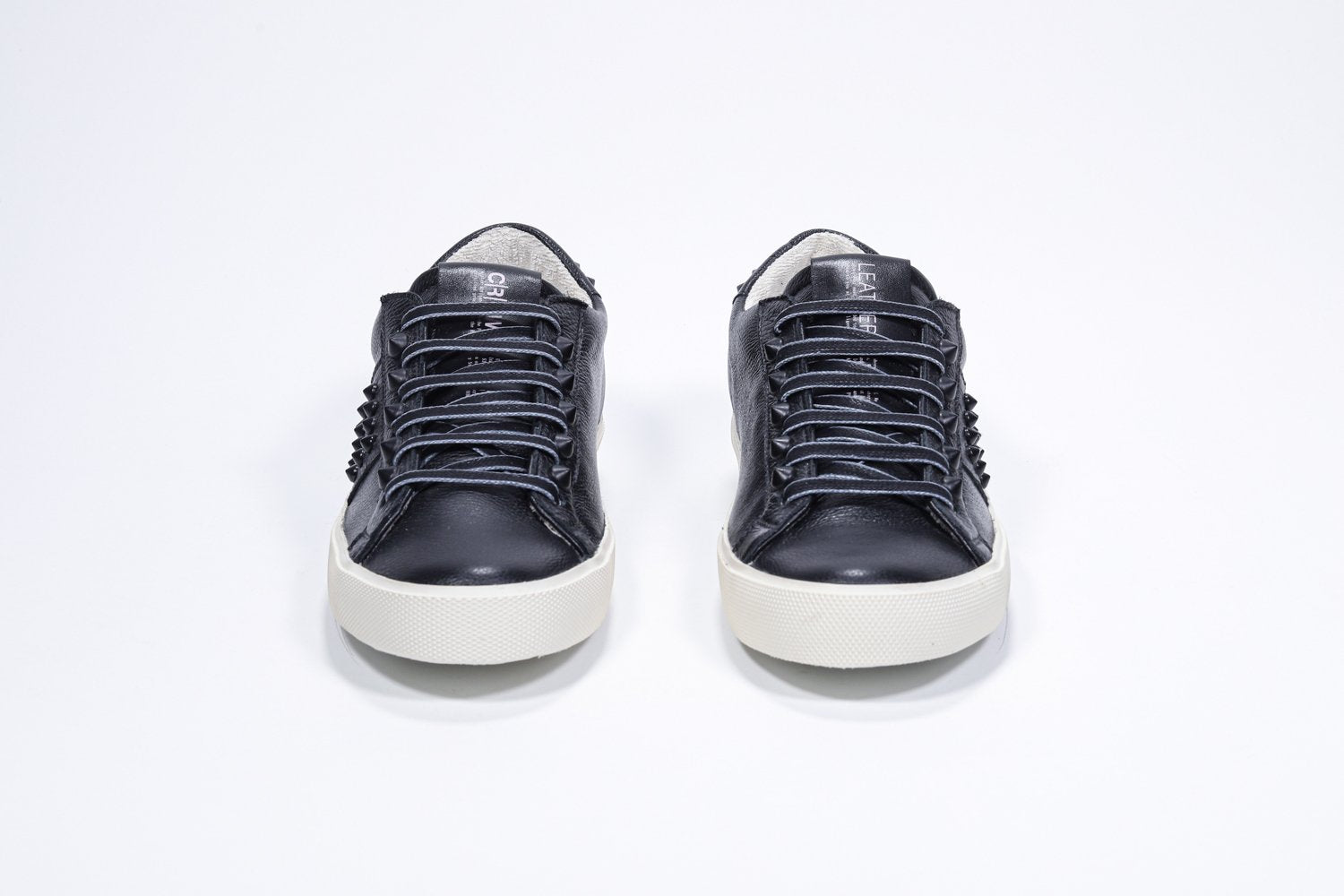 Vue de face de la chaussure noire sneaker. Tige en cuir avec clous et semelle en caoutchouc vintage.