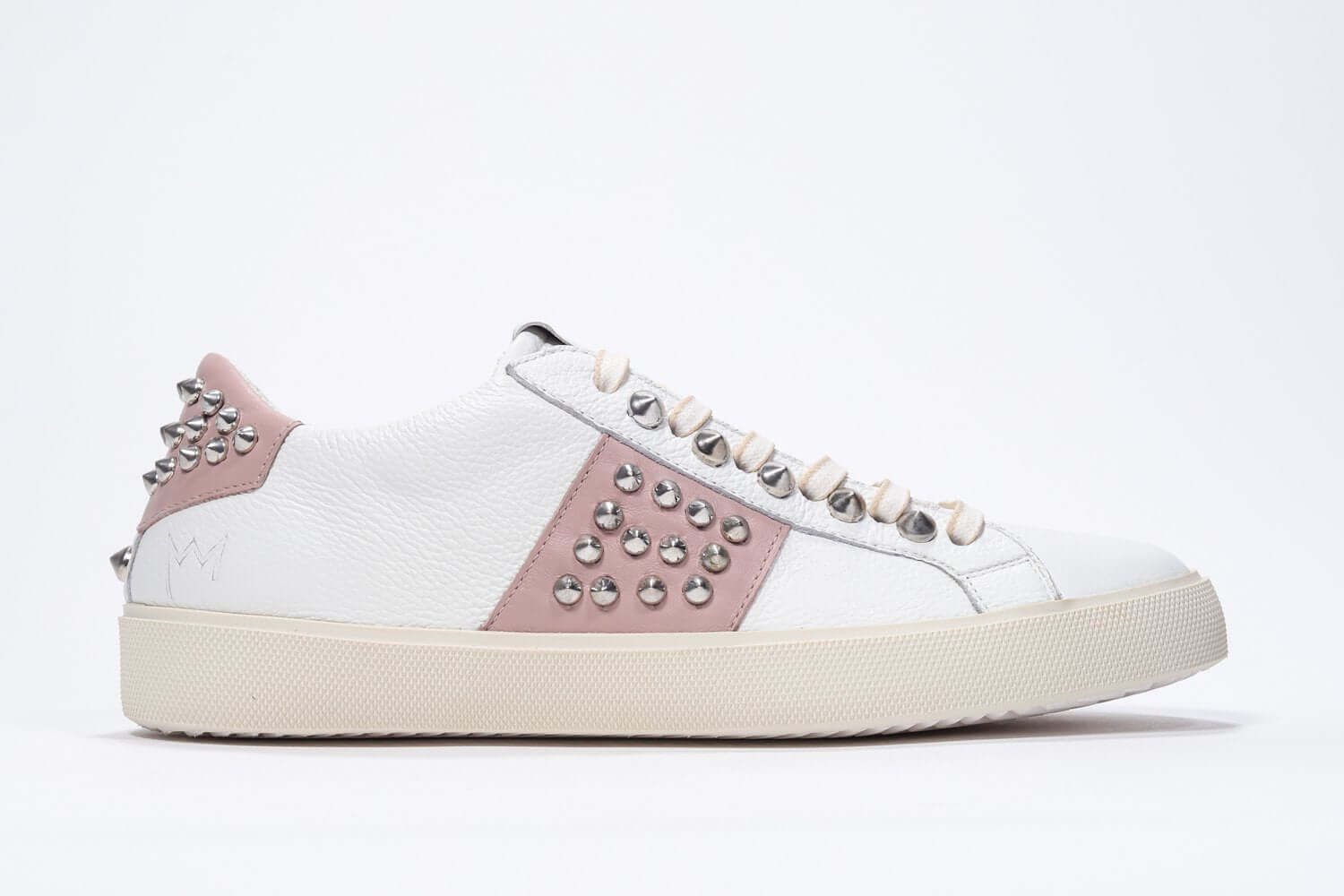 Side profile of low top white and pale pink sneaker. Full leather upper with studs and vintage rubber sole.