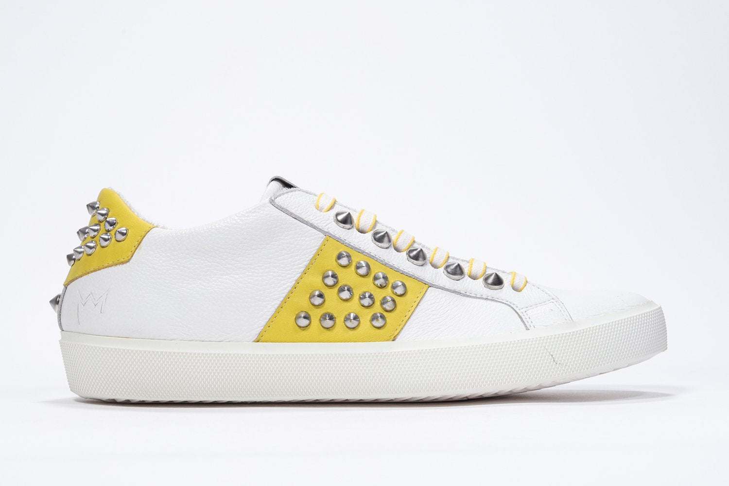 Seitliches Profil des weißen und gelben Low Top sneaker. Obermaterial aus Vollleder mit Nieten und weißer Gummisohle.