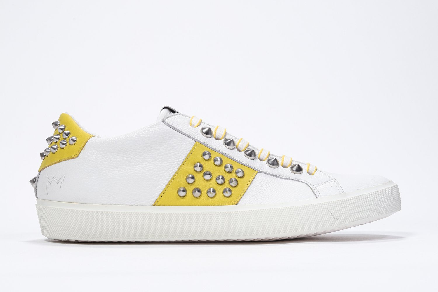 Side profile of low top white and yellow sneaker. Full leather upper with studs and white rubber sole.