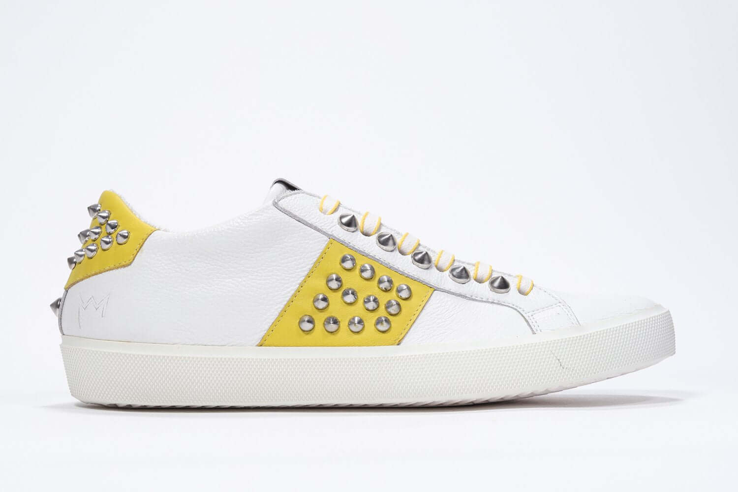 Side profile of low top white and yellow sneaker. Full leather upper with studs and white rubber sole.