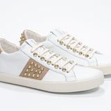 Three quarter front view of low top white and cuoio sneaker. Full leather upper with studs and vintage rubber sole.