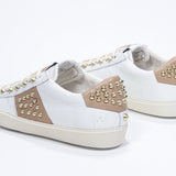Three quarter back view of low top white and cuoio sneaker. Full leather upper with studs and vintage rubber sole.