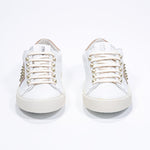 Front view of low top white and cuoio sneaker. Full leather upper with studs and vintage rubber sole.