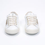 Front view of low top white and cuoio sneaker. Full leather upper with studs and vintage rubber sole.