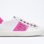 Profil latéral d'un bas blanc et rose néon sneaker. Tige en cuir avec clous et semelle en caoutchouc blanc.