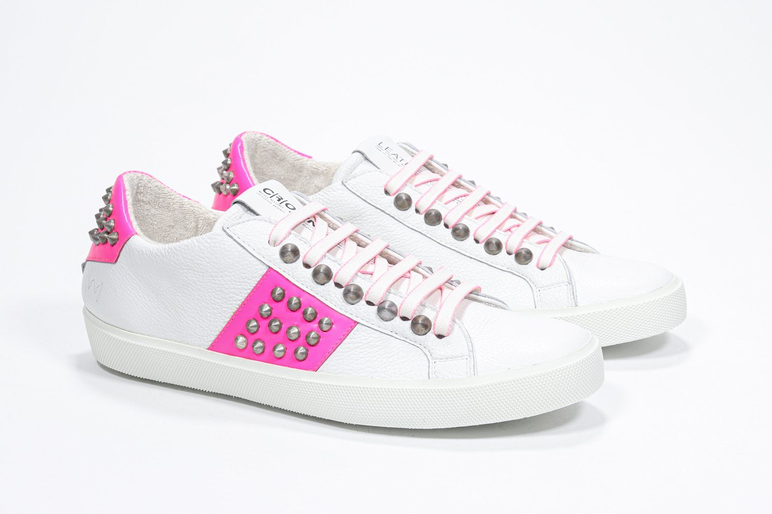 Tre quarti di BASSE bianco e rosa neon sneaker. Tomaia in pelle con borchie e suola in gomma bianca.