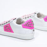 Dreiviertelansicht der Rückseite von Low Top weiß und neonpink sneaker. Obermaterial aus Vollleder mit Nieten und weißer Gummisohle.