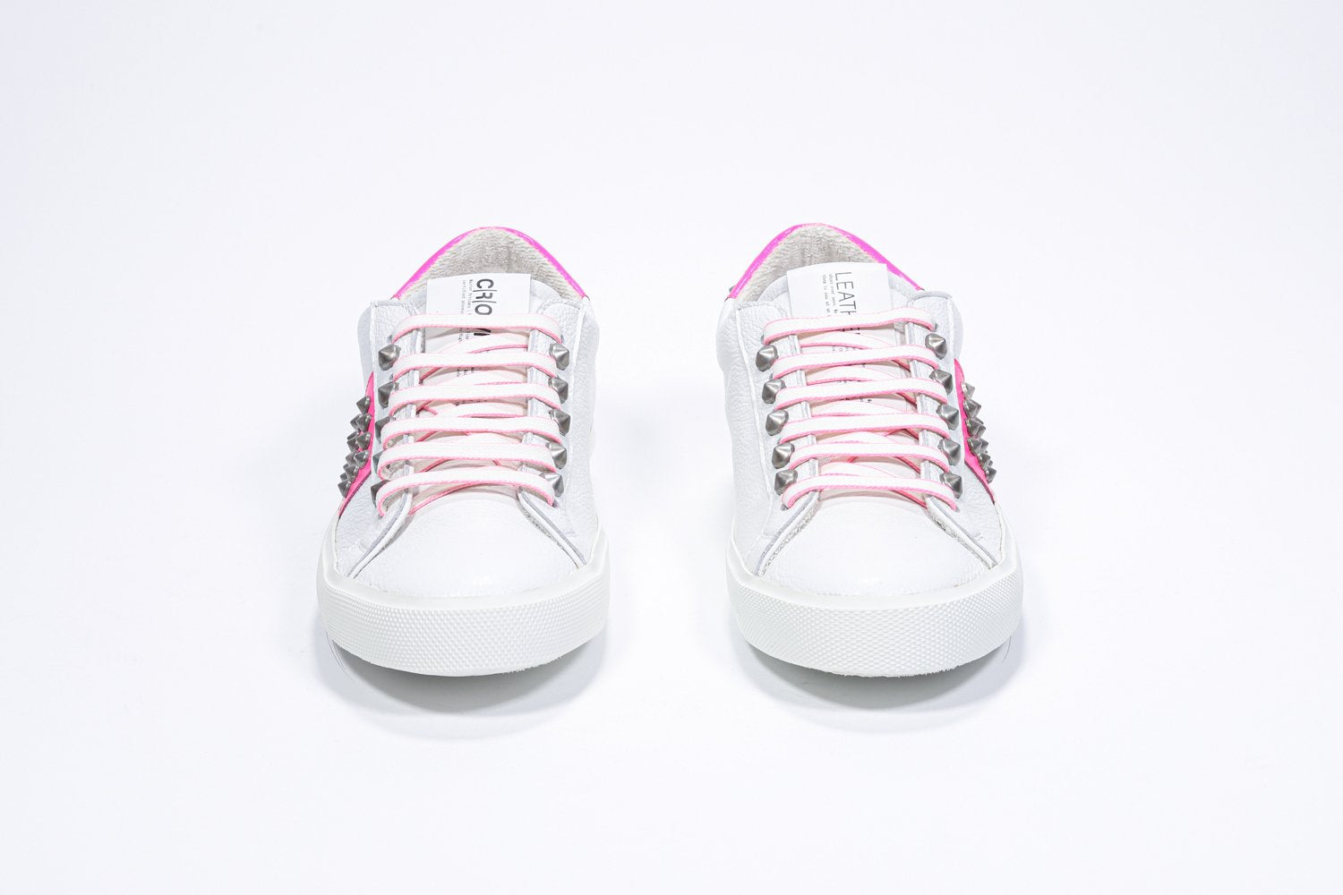 Vue de face de la chaussure blanche et rose néon sneaker. Tige en cuir avec clous et semelle en caoutchouc blanc.