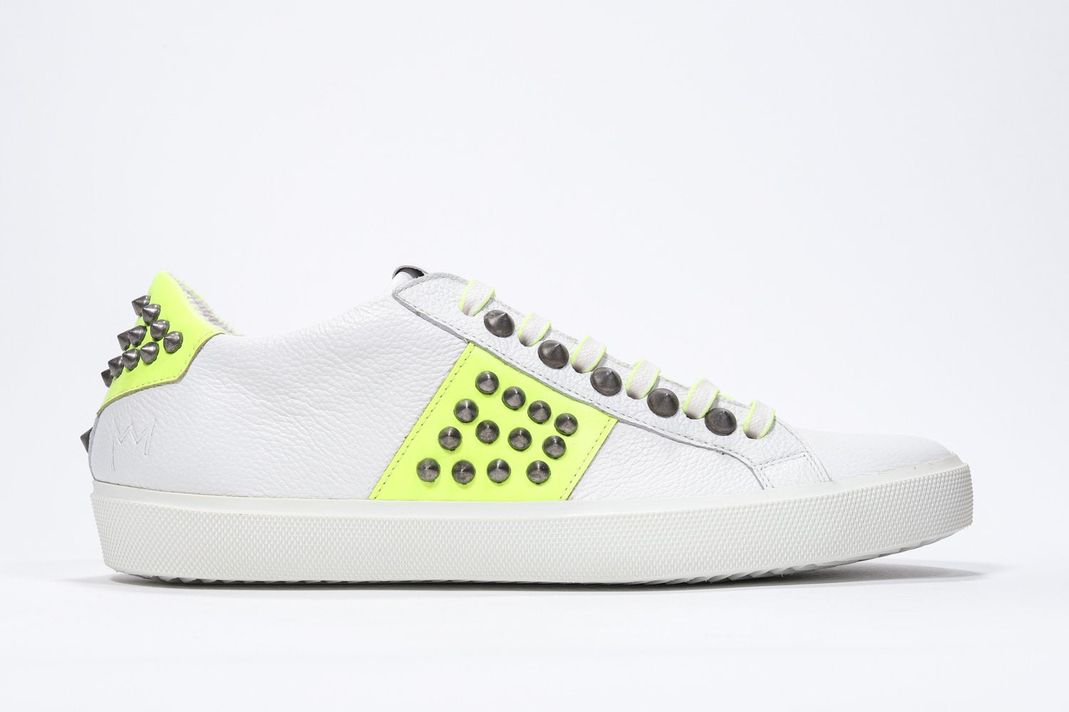 Side profile of low top white and neon yellow sneaker. Full leather upper with studs and white rubber sole.