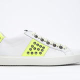 Seitliches Profil des weißen und neongelben Low Top sneaker. Obermaterial aus Vollleder mit Nieten und weißer Gummisohle.